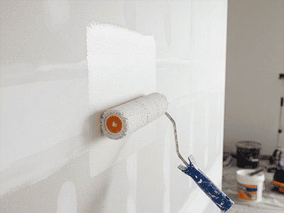 A paint roller applying a coat of white sealer to a new, unpainted gyprock wall.